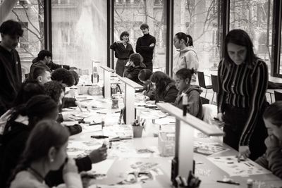 Adolescents assis en train de faire du collage, lors d'un atelier créatif au Centre Pompidou.
