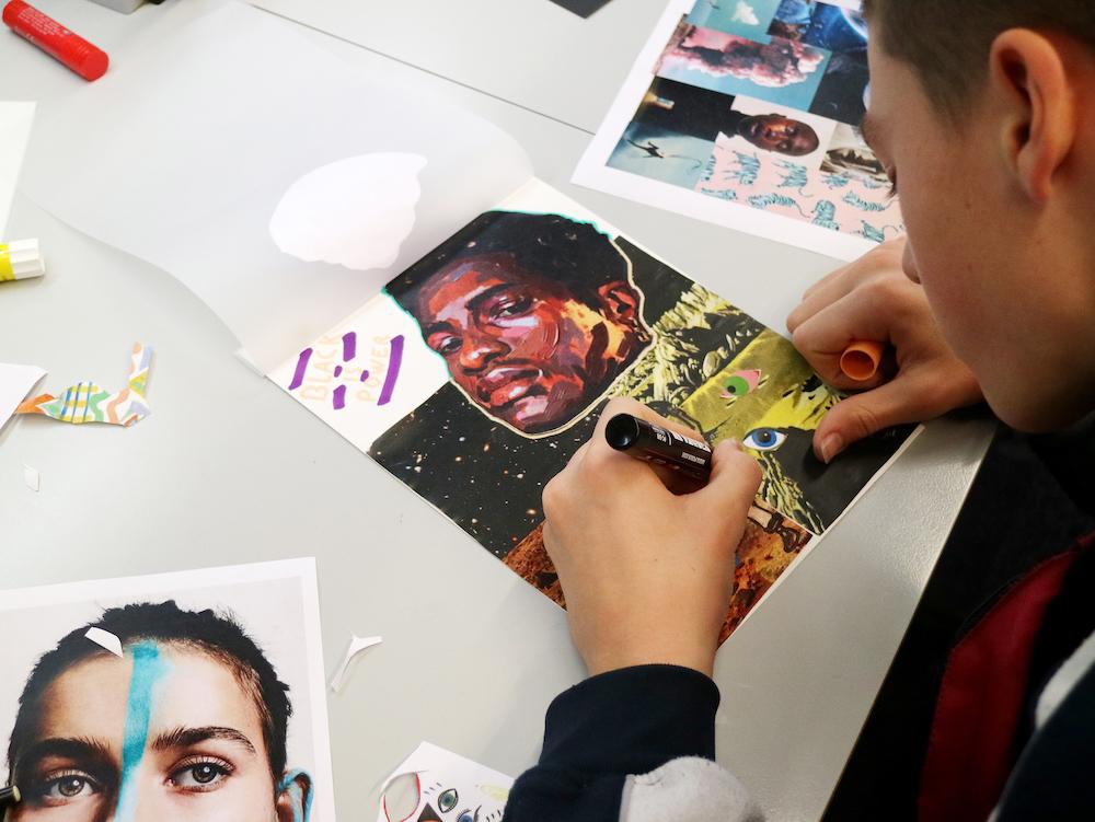 A teen drawing on a board, where 'black is power' can be read