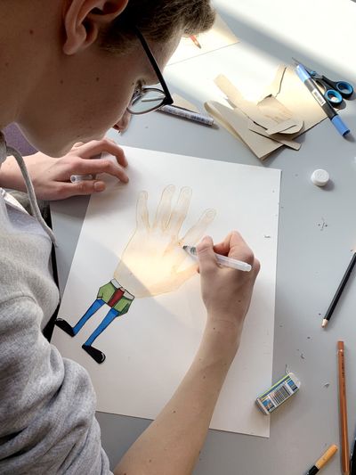 Adolescent en train de colorier le dessin d'une main