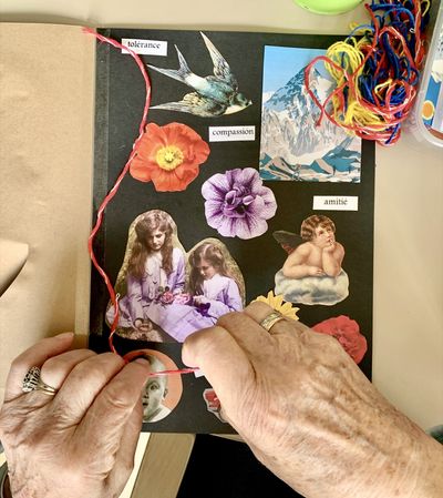 Mains de personne âgée qui travqille sur carnet en papier kraft avec collage d'images.